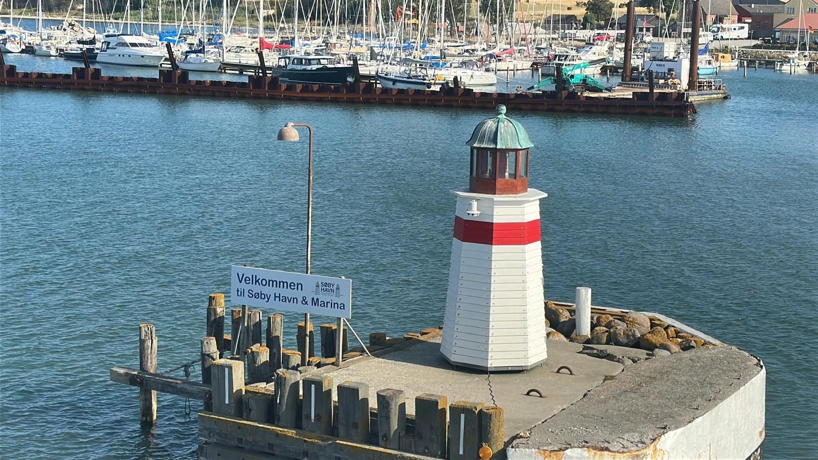 Kleine vuurtoren bij de haveningang van Søby met welkomstbord