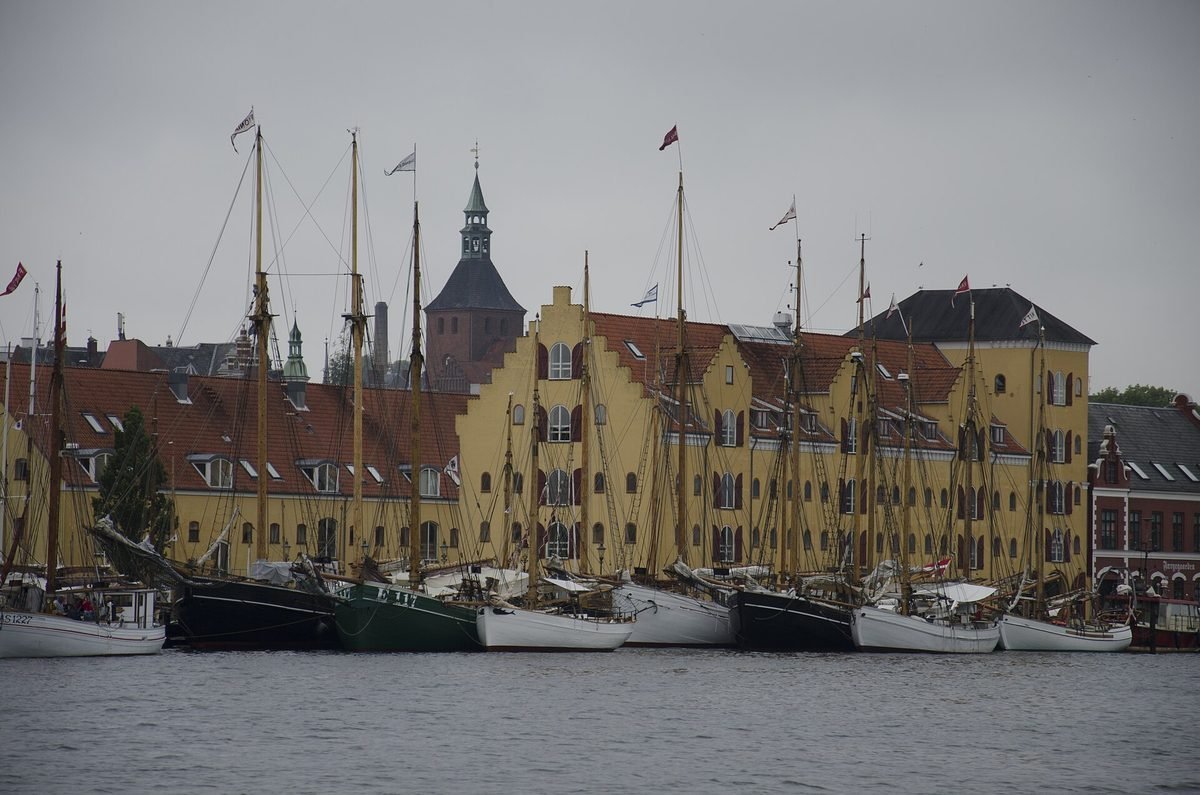 Haven van Svendborg met historische zeilschepen voor gele pakhuizen