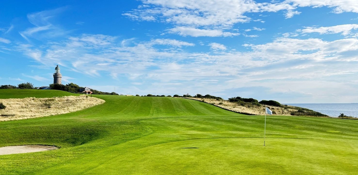 Green van Ærø Golf Klub met vlag en de vuurtoren op de achtergrond