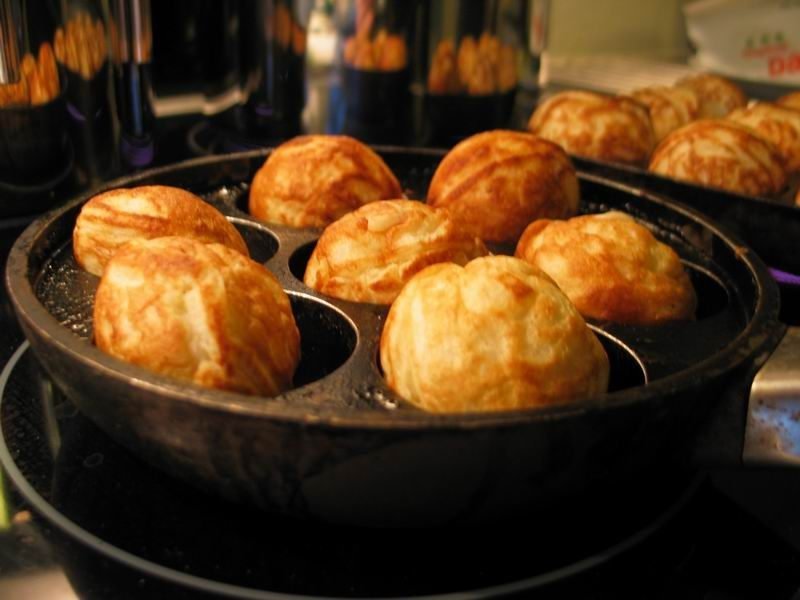 Goudbruine æbleskiver in een gietijzeren æbleskiverpan