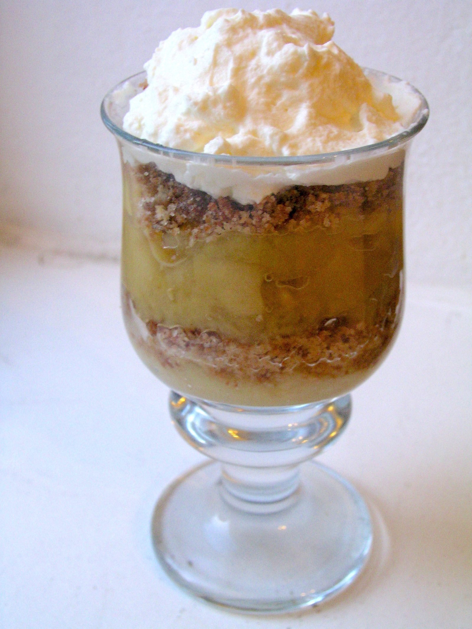 Deens appeldessert in een glas met laagjes appelcompote, geroosterde kruimels en slagroom