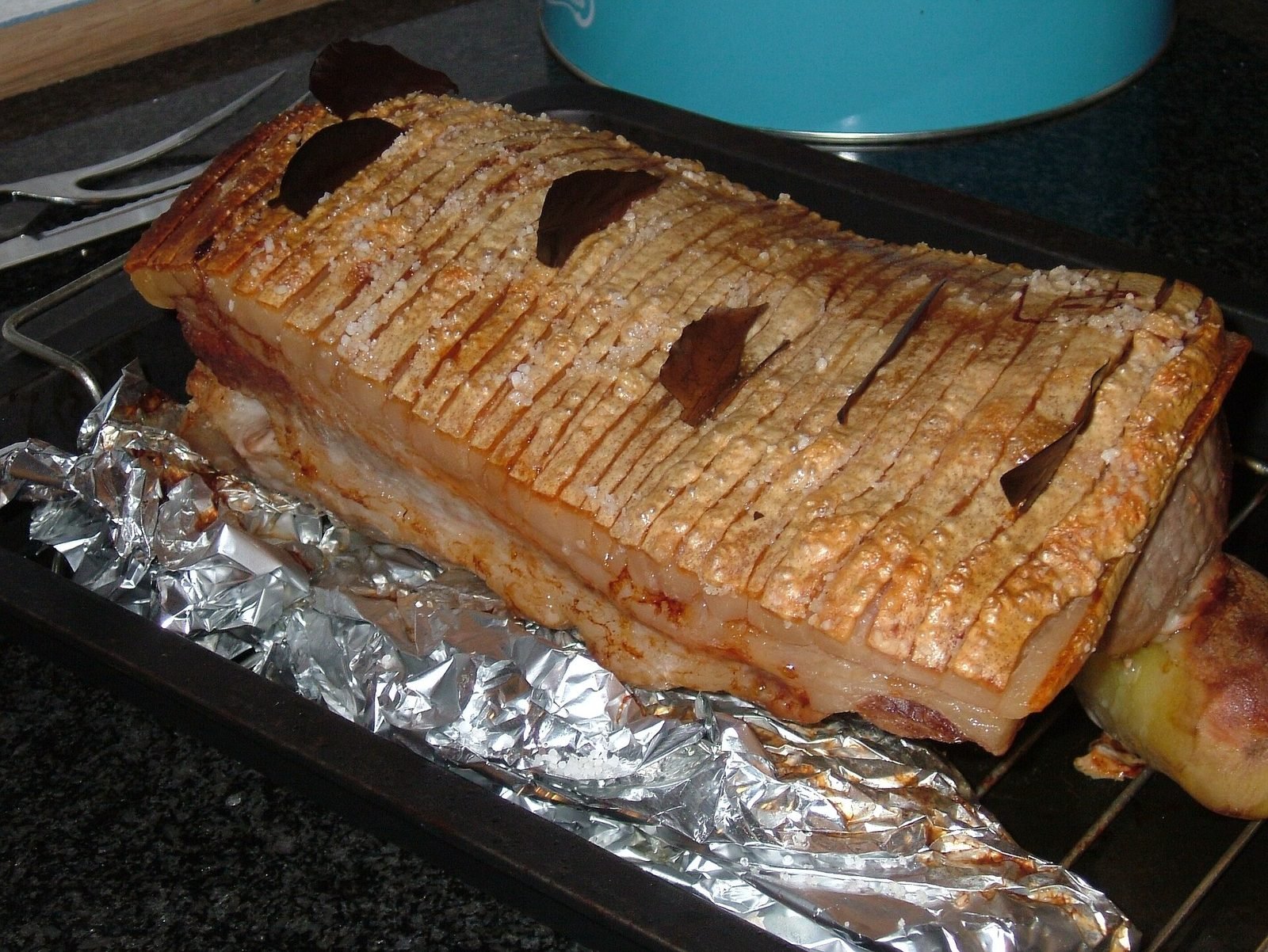 Flæskesteg met krokant gebraden, ingesneden zwoerd en laurierblaadjes op een ovenrooster