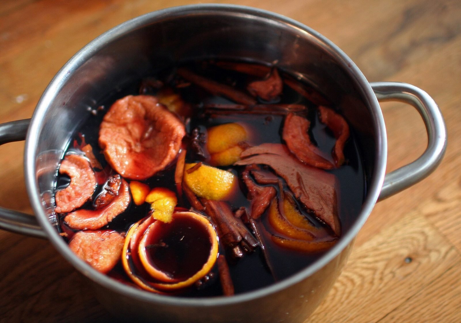 Gløgg in een pan met sinaasappelschijfjes en specerijen